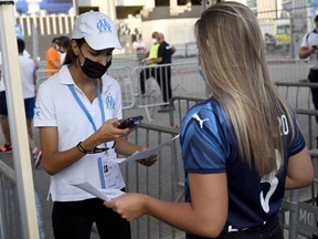An employee checks a fan's health pass at the entrance of the Orange Velodrome Stadium, prior to the football match in Marseille, France, on July 31.