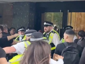 Anti-vaccine demonstrators and security officers clash near entrance of BBC White City building during a protest in London, on Aug. 9, 2021, in this still image taken from a social media video.