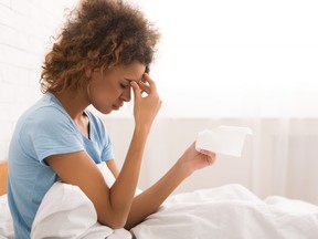 African-american sick woman with runny nose, sitting in bed