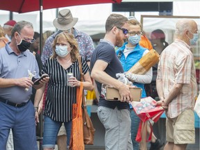 People wear face masks while shopping at a market in Montreal, Saturday, August 7, 2021, as the COVID-19 pandemic continues in Canada and around the world.