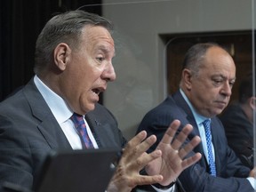 Premier François Legault, left, responds to reporters' questions while Quebec Health Minister Christian Dubé looks on during a news conference on Tuesday.