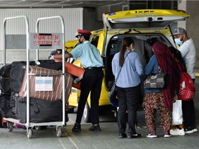 A porter loads luggage of recently arrived air travellers from New Delhi, after Canada's government temporarily barred passenger flights from India and Pakistan for 30 days, at Vancouver International Airport in Richmond, B.C., on April 23, 2021.