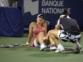 Tunesia's Ons Jabeur of Tunisia, right, checks on Bianca Andreescu of Mississauga, Ont., during third-round play at the Jarry Tennis Centre Thursday night. Andreescu jammed her toe and lost seven of the final eight games after taking an injury timeout.