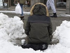 A homeless person panhandles on Ste-Catherine St. last year.