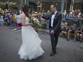 Newlyweds Corey Krakower and Jennifer Smith dance along the Montreal Pride parade route as they head to their wedding ceremony on Aug. 20, 2017.