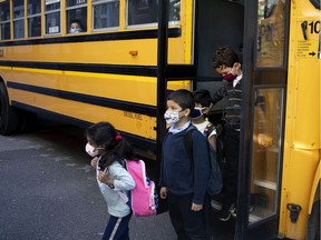 Children get off a school bus at Bancroft Elementary School in Montreal on Aug. 31, 2020.