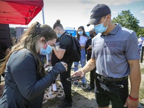 Haley Rhéaume-Jacobson scans Phélix Martineau's QR code at the gate prior to the Concordia Stingers home football game against the Laval Rouge et Or in Montreal on Saturday, Sept. 4, 2021. The game was only open to fans who could prove their vaccination status.