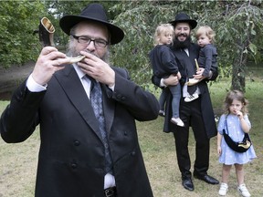 Rabbi Yossi Shanowitz, executive director of Chabad Westmount, blows a shofar at Westmount Park on Monday September 6, 2021 in preparation for Rosh Hashanah, which began Monday at sundown. Looking on are Rabbi Ariel Stern, outreach director for Chabad Westmount, and Stern's children Menachem, left, Mordechai and Yehudis, standing.