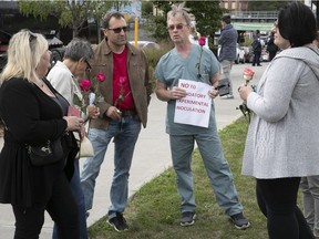 A small crowd gathers for  a "silent vigil" outside the MUHC hospital to protest against COVID-19 public-health measures Sept. 13, 2021.