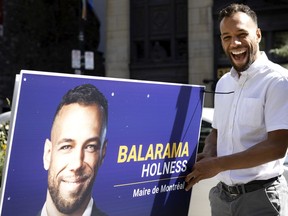 Balarama Holness puts up an election poster outside city hall in Montreal on Friday, Sept. 17, 2021. Holness was informed election posters are not permitted in the Old Montreal area as it is deemed patrimonial. He removed the sign when asked by city hall security.