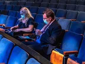 Sylvie Fournier and Marc Dandurand check their phones in the limited seating hall for the Bloc Québécois Monday night at Centre Pierre-Peladeau in Montreal.
