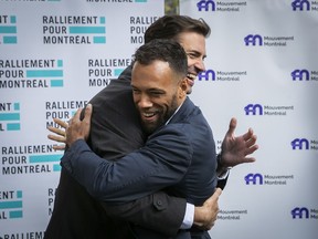 Balarama Holness from Movement Montreal and Marc-Antoine Desjardins, left, from Ralliement pour Montréal, embrace in front of Montreal City Hall on Thursday, as they announced their parties were allying.