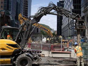 Work crews use a pile driver to install I-beams  as the REM rail project and the Ste-Catherine St. remodelling project collide at the intersection in Montreal on July 16, 2020.