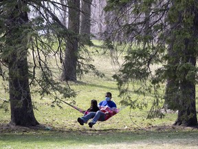 A man and child rock in a hammock in a quiet corner of Mount Royal Park in Montreal.