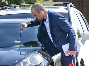 A Montreal police investigator examines a bullet hole in a car at the scene of a shooting in Montreal's Rivière-des-Prairies district Tuesday Aug. 3, 2021.
