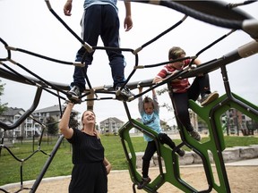 Rebecca Genest watches her children James, 9, top, Noah, 5, and Owen, 8, right, play at a playground near their home in Buckingham, Que.