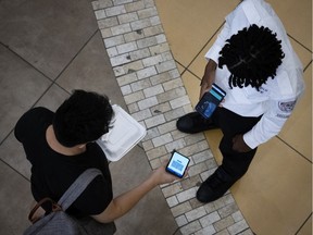 A security guard scans a Montrealer's vaccination status with the VaxiCode Verif app before they are permitted to enter a food court on Wednesday, September 1, 2021.