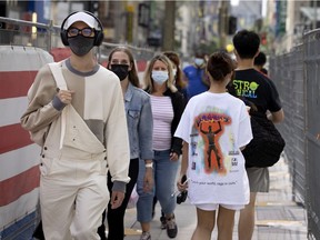 People keep their masks on as a construction detour forces pedestrians in to a very narrow passage on Sainte-Catherine Street on Sept. 1, 2021.