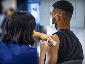 A vaccinator administers a dose of vaccine to Karl Contout at the COVID-19 vaccination site on Park Ave. in Montreal Friday September 10, 2021.