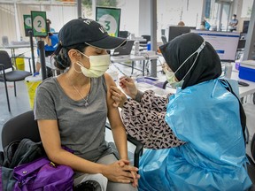 "The world is edging toward 5 million deaths from COVID-19," Lise Ravary writes. "When are we all going to get the message?" Above: Nurul Akidah Lukman administers a dose to Daisy Salgado at a COVID-19 vaccination site on Park Ave.