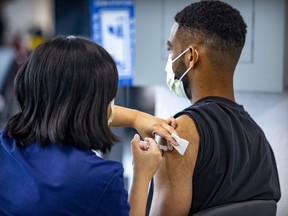 A health-care worker administers a dose of a COVID-19 vaccine to Karl Contout at a vaccination site on Park Ave. on Sept. 10, 2021.