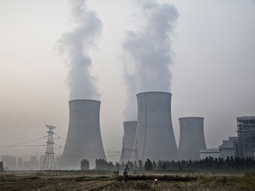 A farmer works his field next to a state-owned coal-fired power plant on June 15, 2017 in Huainan,  Anhui province, China.