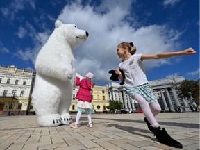 Children play with an environmental protester wearing a costume of a polar bear during a climate march in the Ukrainian capital, Kiev, on Sunday, Sept. 26, 2021.