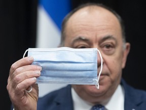 Quebec Health Minister Christian Dubé holds a procedural mask, one of the many they ordered from a Quebec company, during a news conference on the COVID-19 pandemic, Thursday, January 28, 2021 at the legislature in Quebec City.