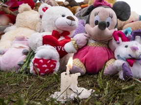 A lone candle burns among stuffed animals in front of the house of a seven-year-old girl who was found in critical condition in her home in Granby, Que. in May 2019. She died a day later in hospital.