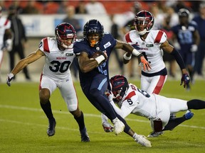 Toronto Argonauts wide-receiver Ricky Collins Jr. (2) attempts to break tackles from Montreal Alouettes' Ty Cranston (30) and Greg Reid (5)  after a pass reception during the first half at BMO Field in Toronto on Friday, Sept. 24, 2021.
