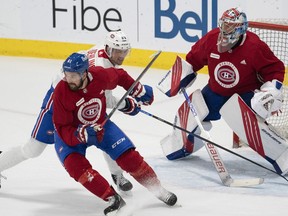 Canadiens' Xavier Oullet, left, battles with Ryan Poehling in front of goaltender Cayden Primeau during training camp Thursday in Brossard.