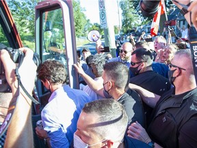 Rocks fly towards Prime Minister Justin Trudeau as he boards his campaign bus after a stop at the London Brewing Co-operative in London, Ont. on Monday September 6, 2021. The rocks found their mark, striking the PM in the back. Derek Ruttan/The London Free Press/Postmedia Network