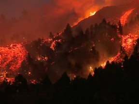 Lava pours out of a volcano in the Cumbre Vieja national park at El Paso, on the Canary Island of La Palma on Sunday, Sept. 19, 2021, in this screen grab taken from a video.