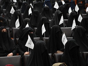 Veiled students hold Taliban flags as they listen women speakers before a pro-Taliban rally at the Shaheed Rabbani Education University in Kabul on September 11, 2021.