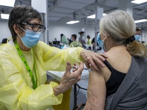 Retired nurse Jennifer Martin vaccinates Lisette Bashour at a COVID-19 vaccination site at Décarie Square in Montreal on Monday, March 1, 2021.