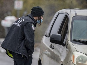 A security guard at a barricade speaks to a car leaving the Tosh Jewish community in Boisbriand, north of Montreal Monday March 30, 2020.  The Hasidic community had been quarantined after an outbreak of COVID -19.