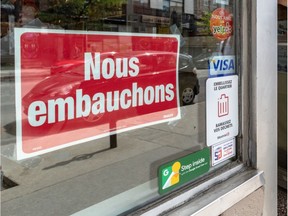 A "We're hiring" sign is seen in Montreal on May 30, 2019. According to a new poll by the Canadian Federation of Independent Business, more than half of small business owners say they’re working more hours as a result of the labour situation.