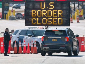 US Customs officers speaks with the occupants of a car at the US/Canada border in Lansdowne, Ontario, on March 22, 2020.