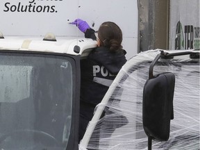 Montreal police crime scene investigator examines a bullet hole in one of five trucks that were the targets of gunshots in a parking lot in the industrial park of the Lachine borough Saturday October 2, 2021.