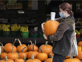 Adele Dukic keeps her eyes on her coffee cup as she carries off the pumpkin she just purchased at the Jean-Brillant Neighbourhood Market on Monday October 4, 2021.