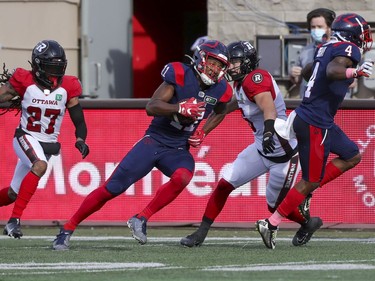 Montreal Alouettes receiver Kaion Julien-Grant runs with the ball between Ottawa Redblacks Sherrod Baltimore, left, and Antoine Pruneau while following the block of team-mate Quan Bray, after making a catch during Canadian Football League game in Montreal Monday October 11, 2021.