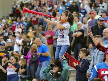 Megan Granger stands on her mother Sylvie's shoulders as she blows her horn to celebrate Montreal Alouettes last minute touchdown against the Ottawa Redblacks during Canadian Football League game in Montreal Monday October 11, 2021.