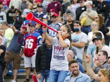 Megan Granger stands on her mother Sylvie's shoulders as she blows her horn to celebrate Montreal Alouettes last minute touchdown against the Ottawa Redblacks during Canadian Football League game in Montreal Monday October 11, 2021.