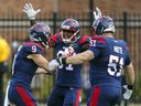 Montreal Alouettes Jake Weineke, left, celebrates a first half touchdown against the Ottawa Redblacks with teammates Eugene Lewis and Kristian Matte during the Canadian Soccer League game in Montreal on Monday, Oct. 11, 2021.
