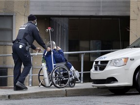 A Montreal police officer helps a patient in a wheelchair to the emergency ward of the Maisonneuve-Rosemont Hospital. The SPVM's new unit aims to build links with the communities they serve.