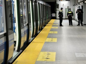 STM inspectors keep an eye on a near-empty métro platform at the Berri station in Montreal on May 4, 2020.