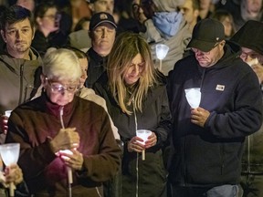 Sister-in-law Marie-France Héneault, centre, attends a candle-light vigil in Lachine Oct. 18, 2021, for Montreal firefighter Pierre Lacroix, who drowned during a rescue operation.