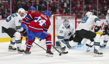 The puck hops over Nick Suzuki's stick in front of San Jose Sharks goalie Aidin Hill during first period at the Bell Centre Tuesday, Oct. 19, 2021.  Sharks' Erik Karlsson, left, and Logan Couture flank Suzuki.