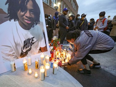 A woman adds candle to a vigil for 16-year- old Jannai Dopwell-Bailey in Montreal on Friday, Oct. 22, 2021.  The youth died after being stabbed outside his school earlier in the week.