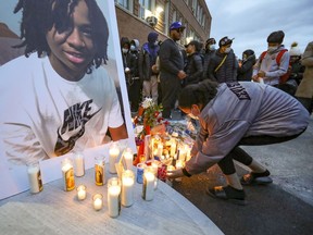 A woman adds a candle to a vigil for Jannai Dopwell-Bailey in Montreal on Oct. 22, 2021. The 16-year-old died after being stabbed outside his school earlier that week.
